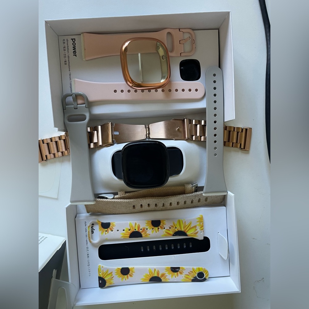 Black Fitbit versa 3 with 6 bands and other accessories